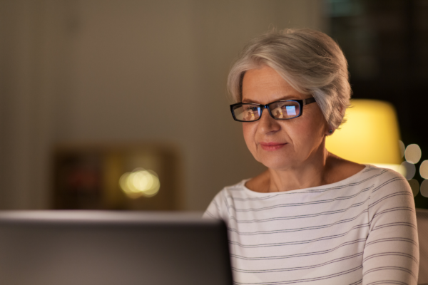 Woman with glasses, sitting in front of laptop computer