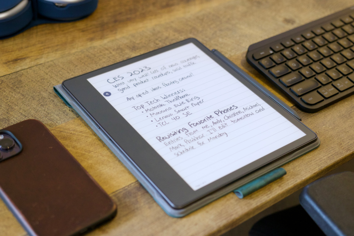 A Kindle Scribe tablet laying on a wood desk beside a keyboard