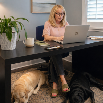 April: Tracy working in her office with dogs sleeping at her feet